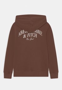 Felpa marrone con cappuccio e lacci, decorata con un logo grafico bianco che riporta "Abercrombie & Fitch New York" sulla parte superiore della schiena. Texture morbida.