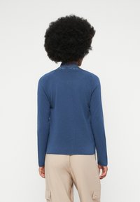 Μακρυμάνικο πουλόβερ από σκούρο μπλε πλέ knitted με στρογγυλή λαι�μόκοψη και δαντελένια λεπτομέρεια στο κολάρο. Απαλή υφή και εφαρμοστή γραμμή στη μέση.