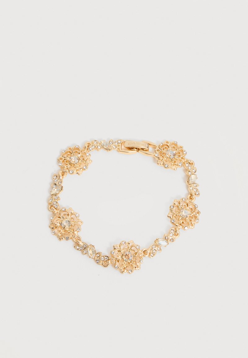 Χρυσό βραχιόλι με λουλουδάτο σχέδιο, διαφανείς πολύτιμους λίθους και ορθογώνιο κούμπωμα σε ανοιχτό γκρι φόντο.