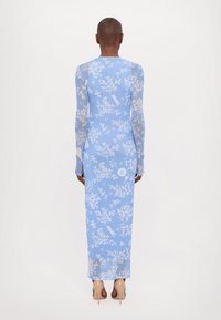 Robe à manches longues, à fleurs bleues, en matériau transparent, présentant un design ajusté, avec une jupe longue et de délicats accents blancs.