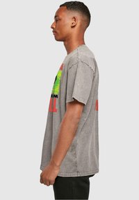 Grijze, oversized graphic t-shirt met een vervaagde afwerking. Bevat kleurrijke geprinte tekst en patronen. Korte mouwen, ronde halslijn, casual pasvorm.