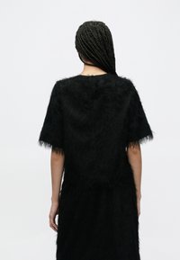 Czarny, puszysty sweter z krótkimi rękawami. Posiada zaokrąglony dekolt i miękką fakturę. Z tyłu znajduje się zapięcie na guzik przy szyi.