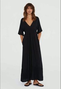 Svart maxi-kjole med dyp V-hals, korte ermer og rynket midje. Laget av lett stoff, har side lommer og en luftig silhuett.