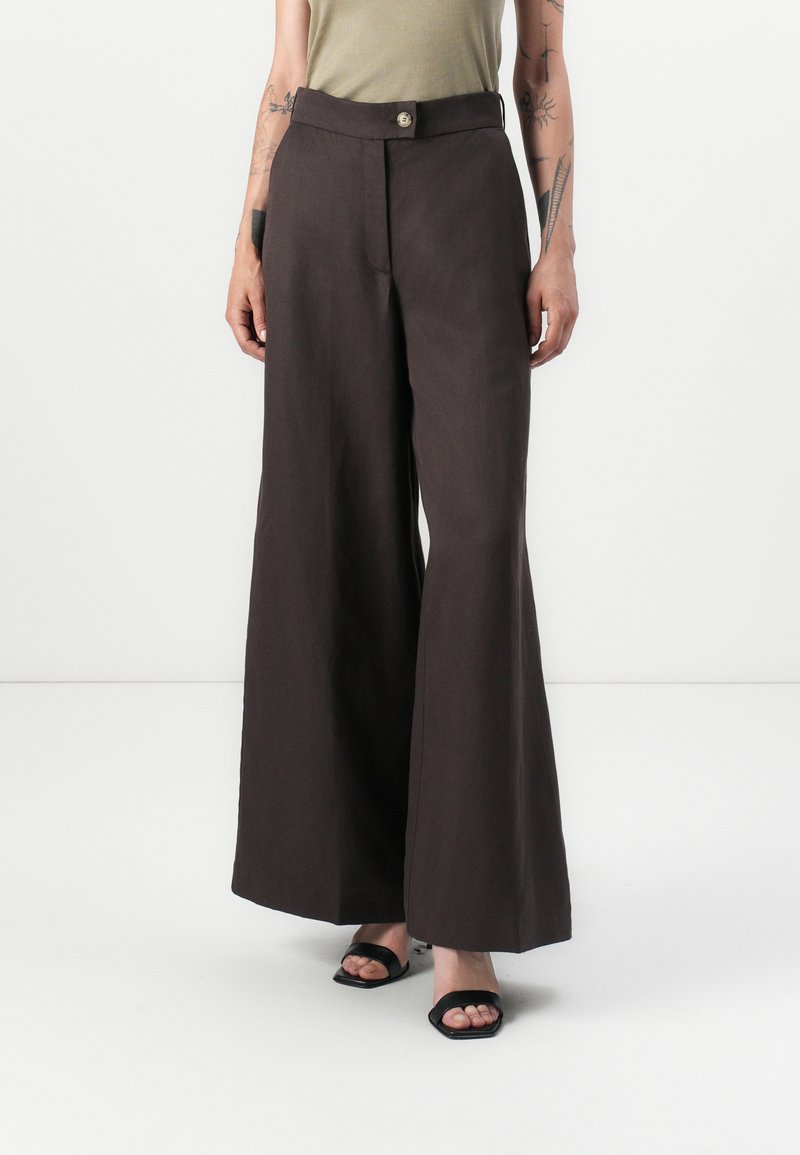 Pantalones de pierna ancha en un tejido marrón oscuro, con cierre de botón, cintura alta y textura suave. Acabados con un diseño minimalista.