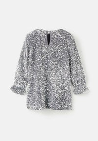 Top argenté à sequins, avec manches longues, poignets à volants et un détail dos en forme de trou clé. Texture lisse avec des sequins scintillants sur toute la surface.