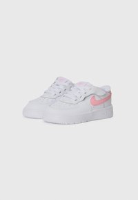 Sneaker Nike bianche con dettagli rosa, con una tomaia in pelle liscia, punta rotonda, dettagli perforati e lacci piatti.