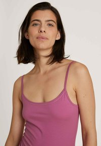 Fitted, sleeveless top in a solid mauve color. Made of soft, stretchy fabric with thin straps and a smooth, unadorned texture.