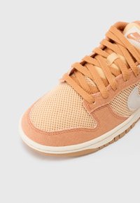 Baskets couleur pêche claire avec une tige en mesh, des détails en tissu et une semelle en caoutchouc. Comprend des lacets beige et un accent logo discret.