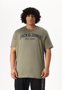 Oliwkowa bawełniana koszulka z krótkim rękawem, okrągłym dekoltem i wyraźnym czarnym napisem "JACK & JONES EST. 1990" na piersi.