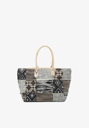 Bolsa tote con diseño de patchwork en patrones geométricos y rayas en negro, blanco y marrón, con asas tejidas beige y una etiqueta redonda colgante.