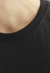 Sort bomulds T-shirt med rund halsudskæring, med en glat tekstur og forstærket syning langs kraven. Ingen synlige grafik eller mønstre.