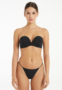 Černý bikiny top bez ramínek s hladkým, vytvarovaným designem a odpovídajícími nízkými tangy. Materiál vypadá pružně a těsně přiléhá.