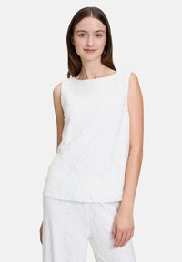 Biała bezrękawnik z fakturowanym falistym wzorem, okrągłym dekoltem i luźnym krojem. Wykonana z lekkiego materiału.