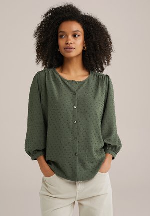 Green button-up blouse with textured fabric, round neckline, and three-quarter puff sleeves, featuring a relaxed fit and subtle dot patterns.