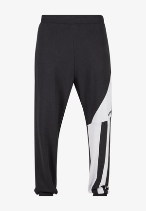 Black sweatpants with white side panel featuring vertical black stripes. Made of soft fabric, with elastic waistband and cuffed hem.