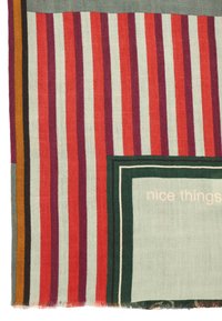 Multicolored woven textile featuring alternating red, purple, and teal stripes, with a green-bordered square displaying "nice things" in light text.