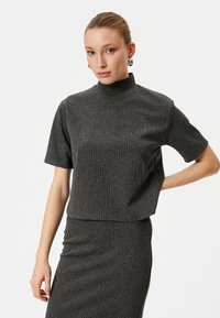 Kortærmet top i kulgrå med høj hals og subtile striber. Lavet af et struktureret materiale, cropped design.