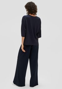 Navy-gestreiftes Oberteil mit weiten Ärmeln, kombiniert mit passenden weiten Hosen. Weicher Stoff und lockere Passform, mit minimalistischem Design und keinen sichtbaren Akzenten.