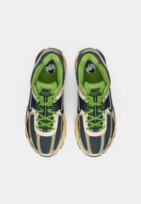 Παπούτσια τρεξίματος Nike με πλέγμα σε ναυτικό μπλε και μπεζ, πράσινα κορδόνια, μαύρες λεπτομέρειες και μαξιλαρωτή σόλα για άνεση.