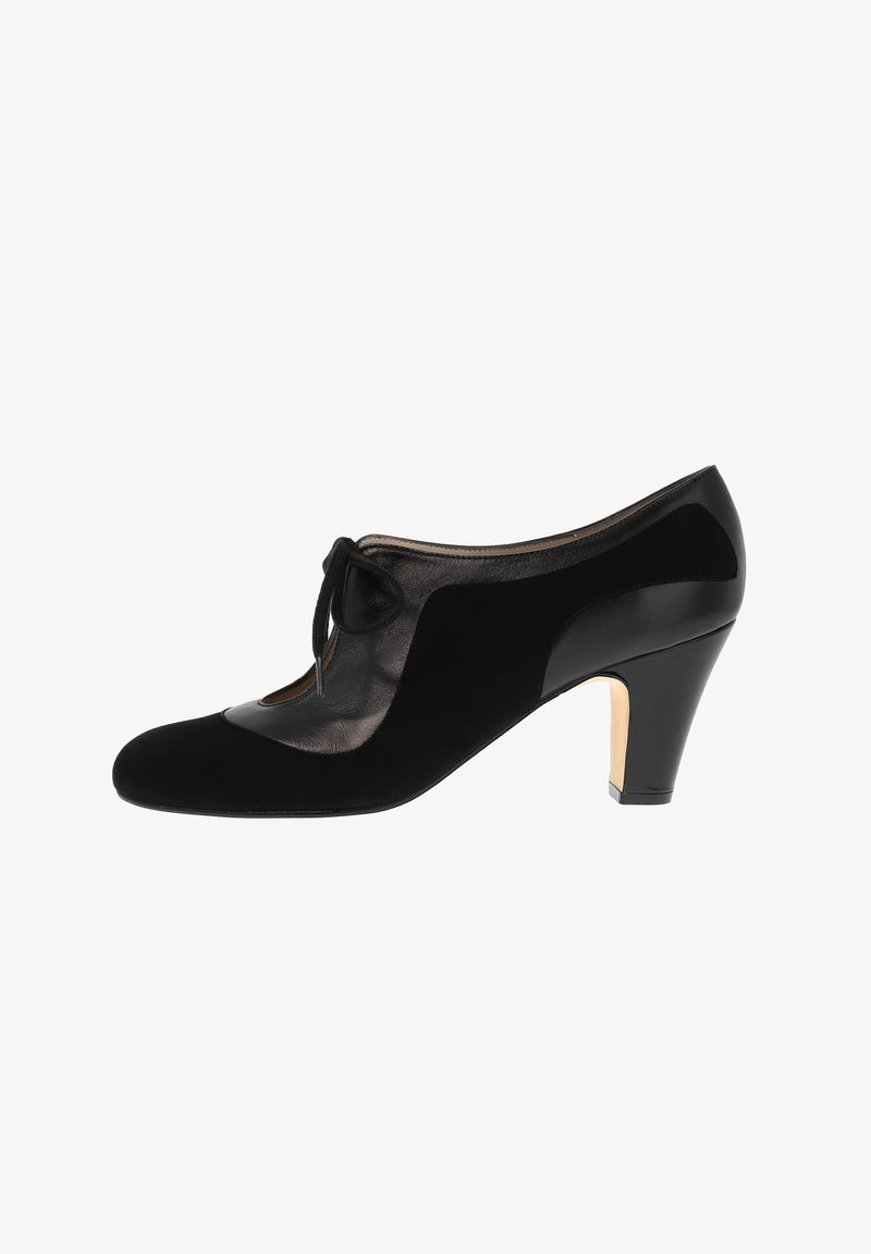 Black high-heeled shoe featuring a combination of suede and shiny leather, with a tied bow detail and cut-out design on the side.
