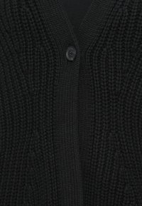 Cardigã preto tricotado com um padrão texturizado, decote em V profundo e um único fecho de botão preto na frente.