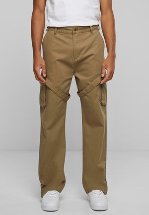 Brune cargo bukser med løs pasform, der har sidelommer og justerbare remme, parret med hvide sneakers og en almindelig hvid t-shirt.