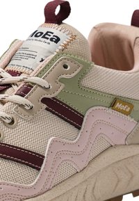 Kreminės tekstūros sportbačiai su šviesiai žaliais ir rožiniais bangelės raštais, tamsiai raudonomis juostelėmis ir tvirtu padu. Yra kilputė ir logotipo etiketė.