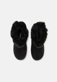 Botines de ante negro con un suave cuello de piel sintética. Diseño de punta redondeada con un forro suave y suela plana.