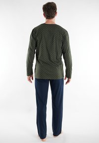 Long-sleeve green shirt with white vertical patterns, paired with navy blue pants. Soft fabric, relaxed fit, minimalistic design.