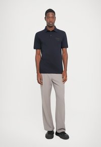 Jūras flotes polo krekls ar īsām piedurknēm, ar toņu logotipu uz krūtīm. Saskaņots ar gaiši pelēkiem, platām biksēm un melnām kurpēm.