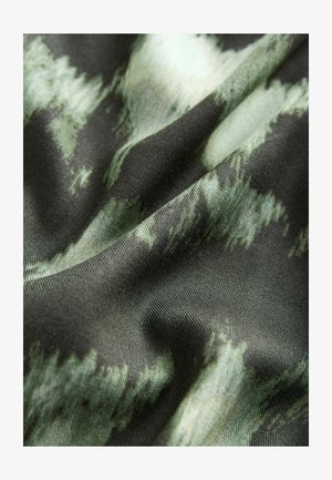 Tyg med en mjuk textur, som har en mörkgrön bas och abstrakta ljusgrön mönster, som visar en svävande, rynkig utseende.