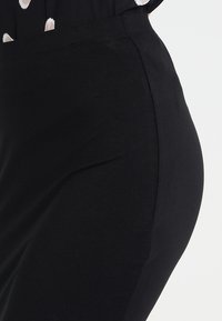 Jupe noire ajustée avec une texture en coton lisse et une couture latérale, dotée d'une ceinture mi-haute et d'un design simple et minimaliste.