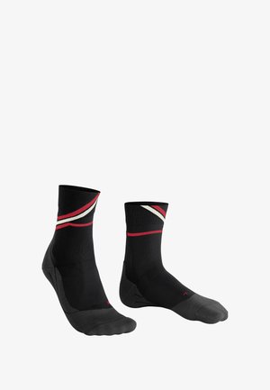 Calze sportive nere con strisce diagonali rosse e bianche nella parte superiore, punta e tallone rinforzati grigi e una texture liscia in tutto il calzino.