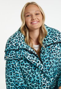 Padded coat v tyrkysové barvě s černým leopardím vzorem. Má velký límec, zapínání na zip a patentky vpředu.