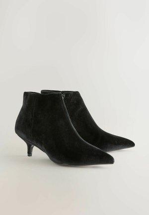 Black velvet ankle boots with a pointed toe and a decorative zipper; features a low kitten heel and a smooth texture.