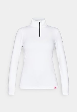 Λευκή μπλούζα με μακριά μανίκια και ψηλό γιακά, με μαύρο μισό φερμουάρ. Διαθέτει μία μικρή ροζ ετικέτα στο ποδόγυρο. Λείο και ελαστικό υλικό.