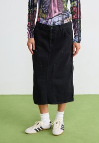 Svart denim midi-skjørt med rett snitt, frontlommer og knappelukking. Kombinert med hvite og svarte idrettssko.