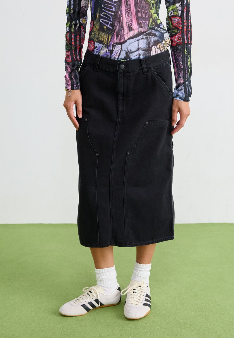 Svart denim midi-skjørt med rett snitt, frontlommer og knappelukking. Kombinert med hvite og svarte idrettssko.