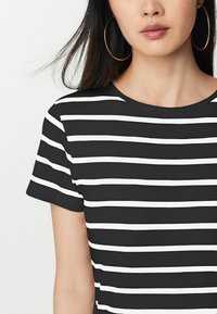 T-shirt rayé noir et blanc avec un col rond et des manches courtes, présentant une texture côtelée et une largeur de rayures uniforme.