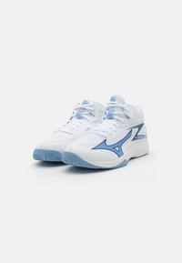 White athletic shoes with blue accents, textured mesh upper, rubber sole, and flat laces. Features a prominent logo on the side.