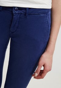 Marinblå bomullschinos med slim fit, med knappstängning, bälteshällor och sidofickor. Slät textur med minimala sömnadsdetaljer.