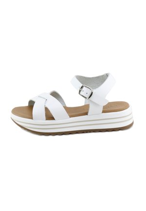 Sandalia blanca con hebilla en la correa del tobillo, tiras delanteras cruzadas, plantilla acolchada color marrón claro y suela blanca gruesa con banda de rodadura a rayas beige.