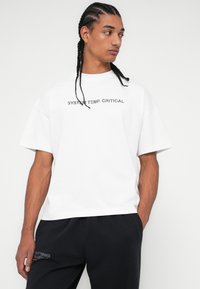 Λευκό κοντομάνικο t-shirt με κείμενο "SYSTEM TEMP. CRITICAL" εκτυπωμένο σε γκρι. Άνετη εφαρμογή με στρογγυλή λαιμόκοψη. Φοριέται με μαύρο παντελόνι.