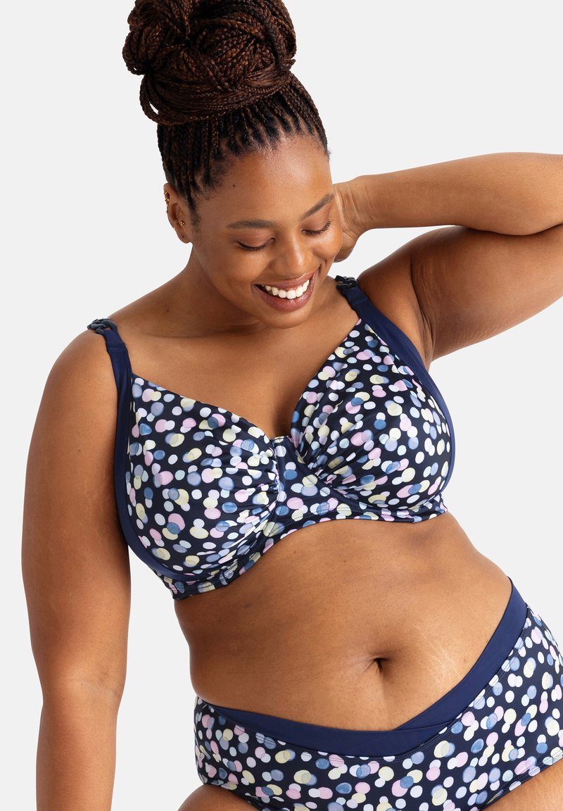 Námornícky modrá podprsenka a nohavičky s bodkovaným vzorom v pastelových farbách. Obsahuje nastaviteľné ramienka a hladký materiál.