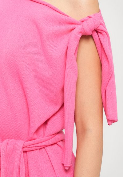 Top roz tricotat cu un design off-shoulder, având mâneci legate și o curea asortată la talie, realizat dintr-un material moale și texturat.