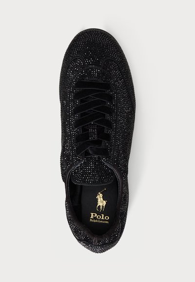 Sneaker nera con superficie texture coperta di piccoli cristalli scintillanti. Presenta lacci neri piatti e un logo dorato sulla soletta.