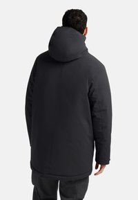 Veste noire isolante avec capuche, présentant un extérieur lisse, une coupe droite et des détails de couture. La vue de dos montre une coupe décontractée.