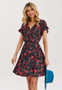 Květinové šaty s černým pozadím, zdobené červenými a modrými květinami, krátké rukávy, výstřih do V a přiléhavý pas s detailem na zavazování.