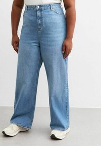 Vaqueros de tiro alto y pierna ancha en denim azul claro. Presentan lazos para cinturón, cierre frontal con botón y diseño clásico de cinco bolsillos.