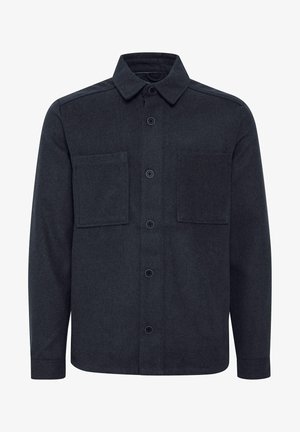 Mørkegrå langermet skjorte med krage, frontlukking med knapper og to brystlommer. Laget av et teksturert stoff.